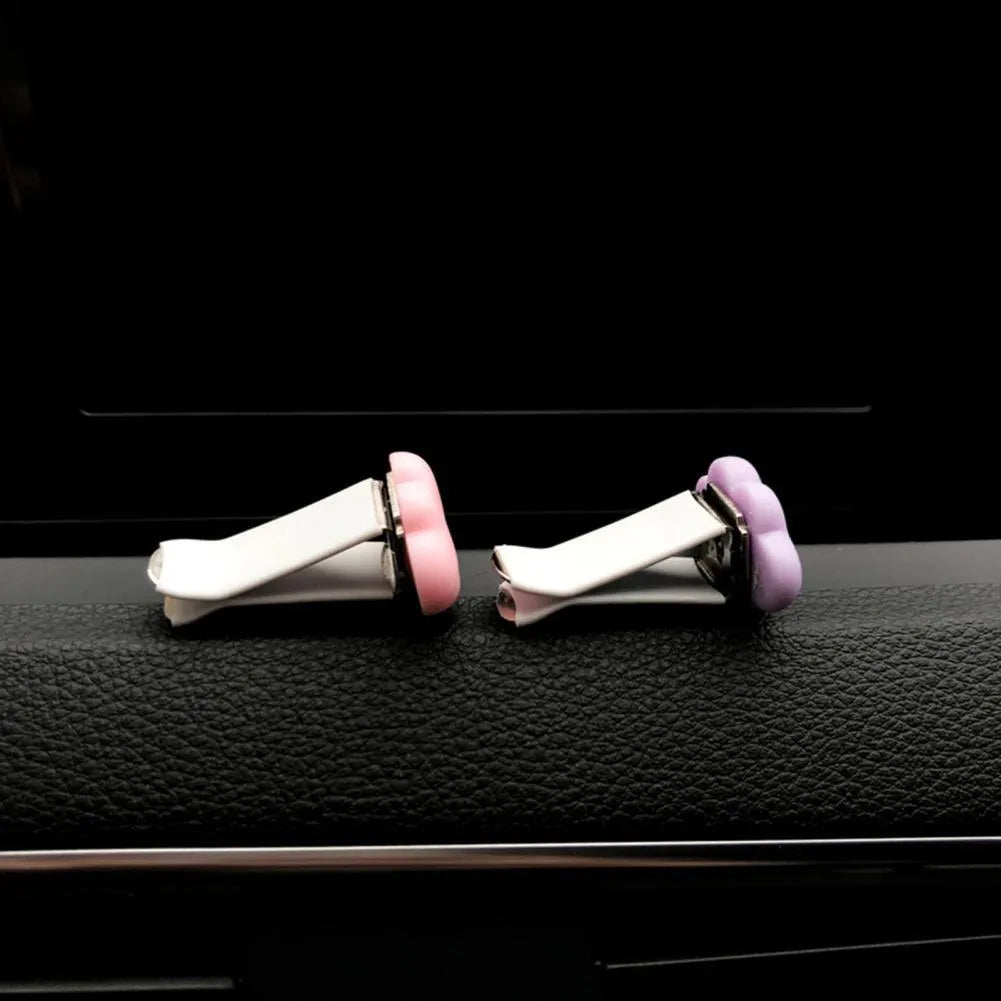 Resin cartoon-style car fragrance clip attached to a vehicle air vent.