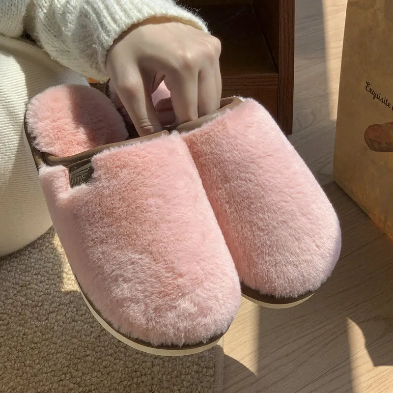 Pair of solid-colour plush winter slippers with a slip-on design and a textured PVC sole.