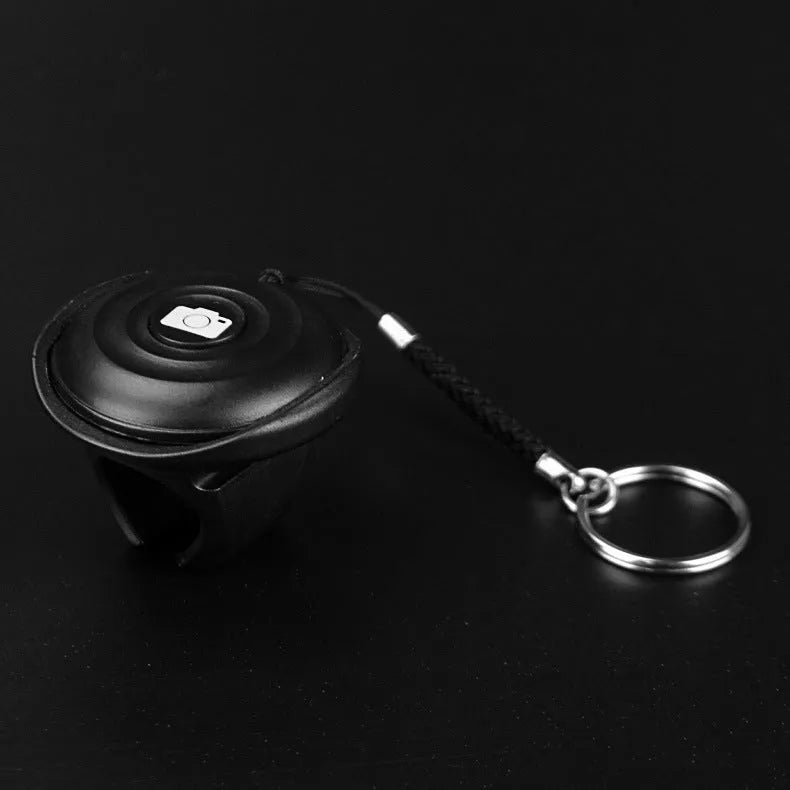 Small black Snap Bluetooth remote shutter on a hand, showing single button.