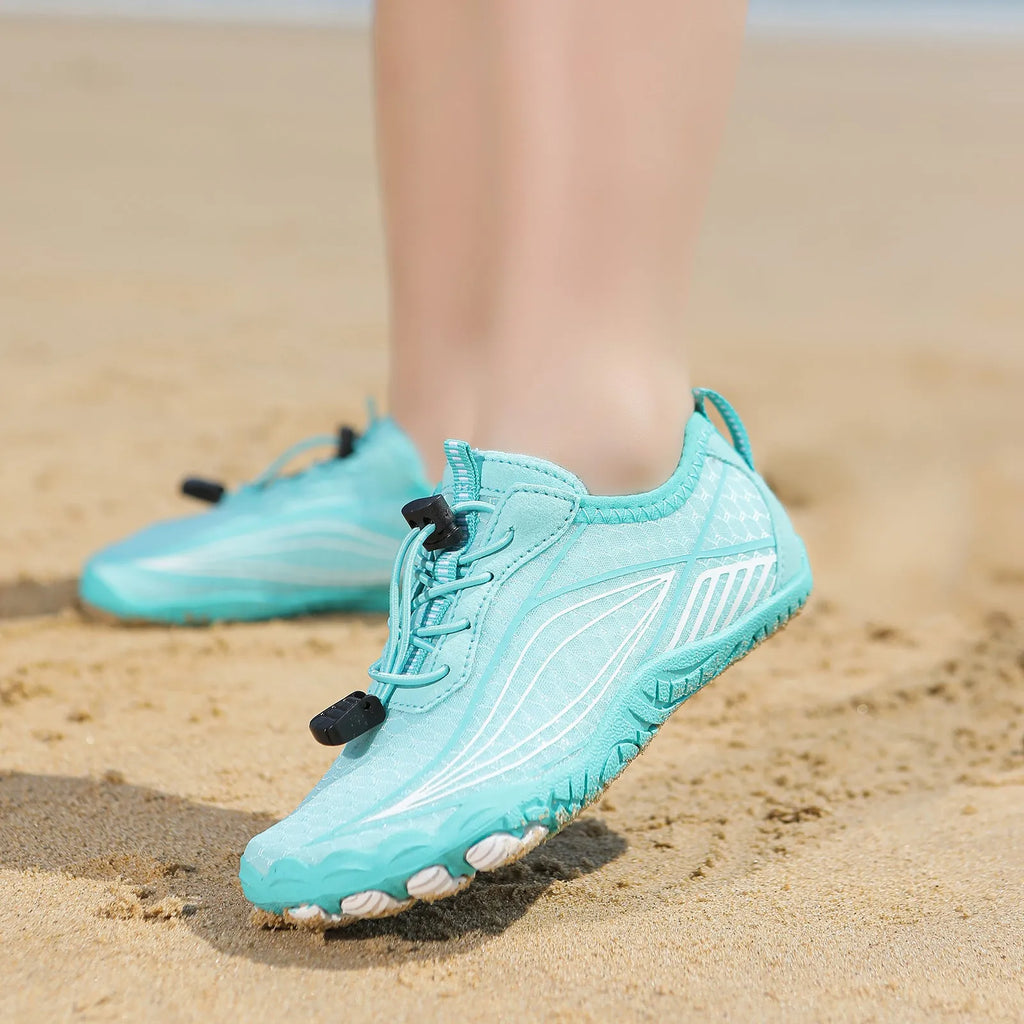 Children's quick-drying water shoes with non-slip rubber soles in multiple colours on a sandy beach.
