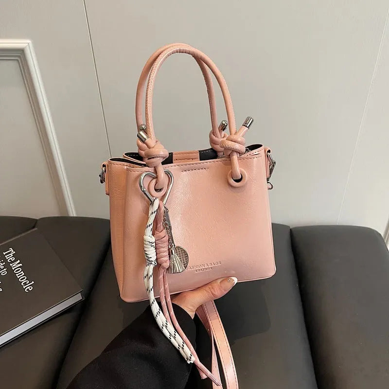 Women's PU one-shoulder bucket messenger bag in black with pendant, showing front view with single strap