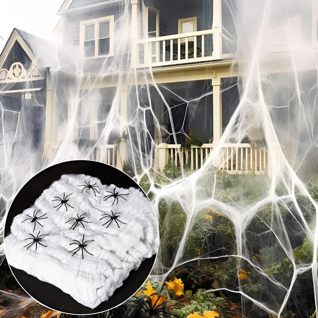 White cotton spider web Halloween decoration with plastic spiders draped over a fence.