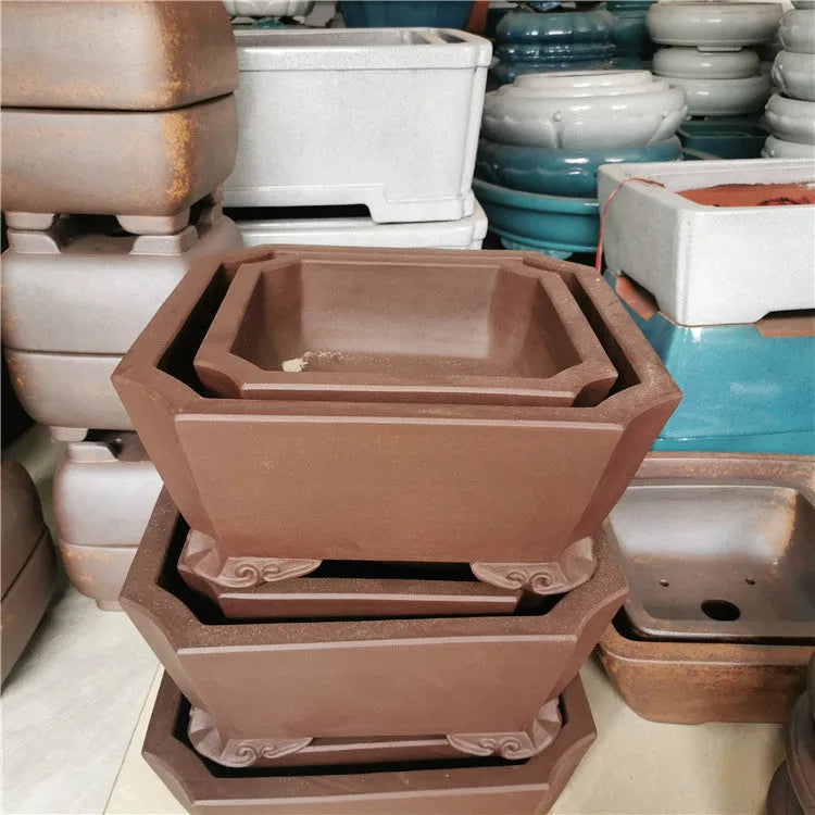 Set of two square stump purple sand flowerpots in brown finish on a flat surface
