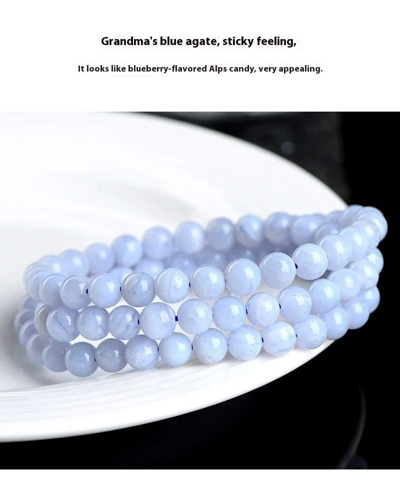 Blue agate bracelet with striped beads and a Ruyi charm on a wrist.