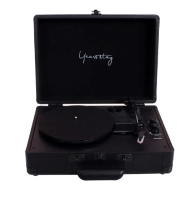 A black leather case Bluetooth turntable for vinyl and film records on a wooden surface.