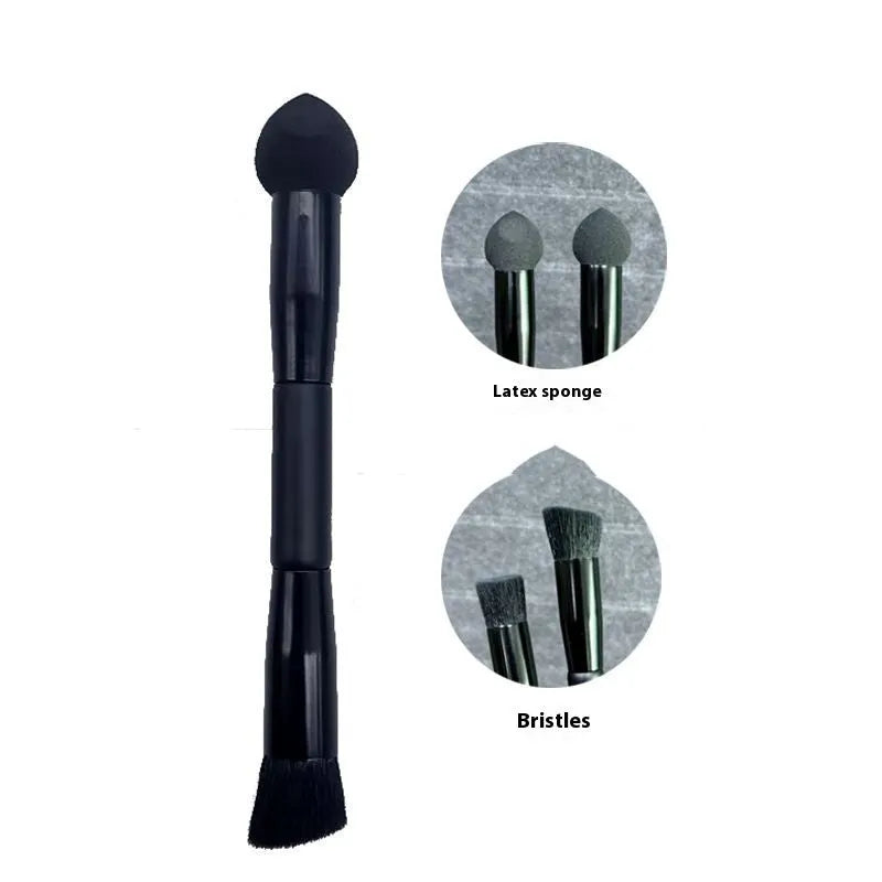 Black wooden handle concealer brush with a grey sponge tip applicator angled for under eye use.