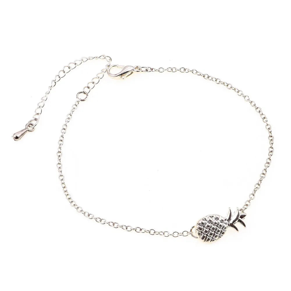 Gold and silver alloy pineapple charm bracelet on wrist, showing adjustable clasp.