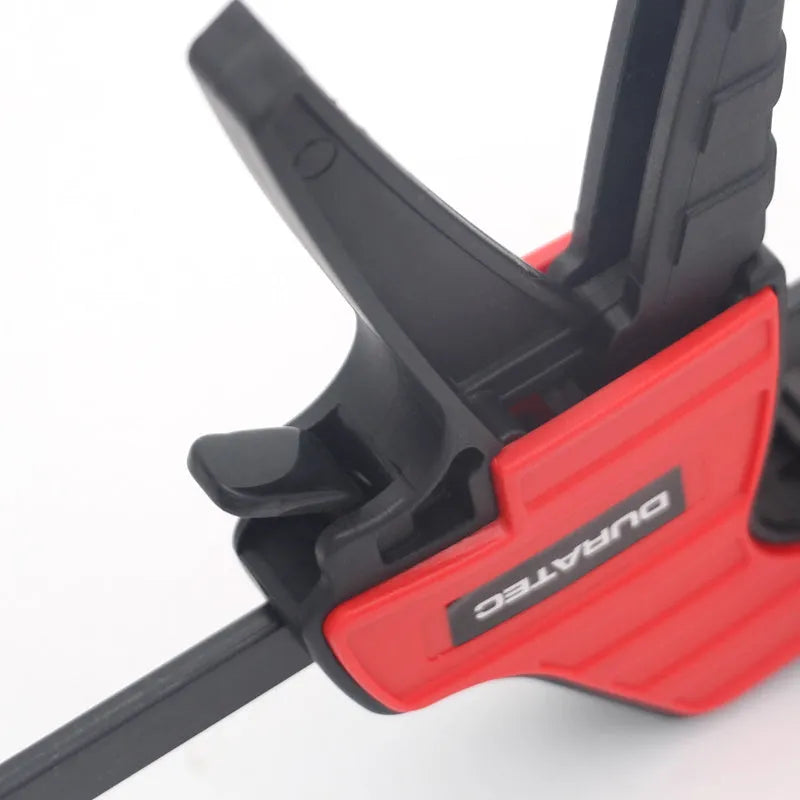 Black plastic woodworking clamp with quick-release trigger and soft rubber protective jaws.