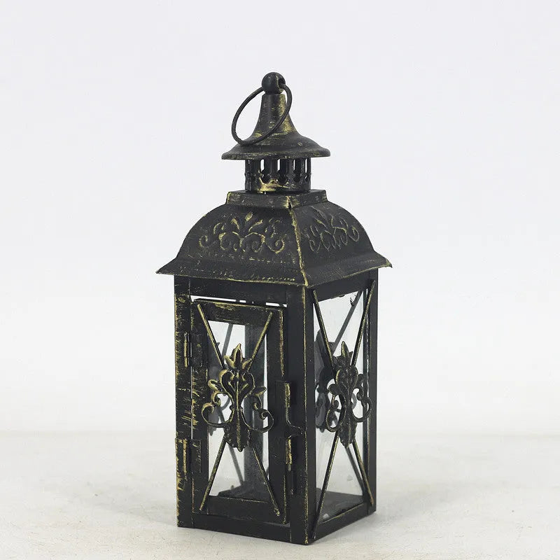 Black wrought iron floor-standing storm lantern with clear tempered glass panels on a garden patio.