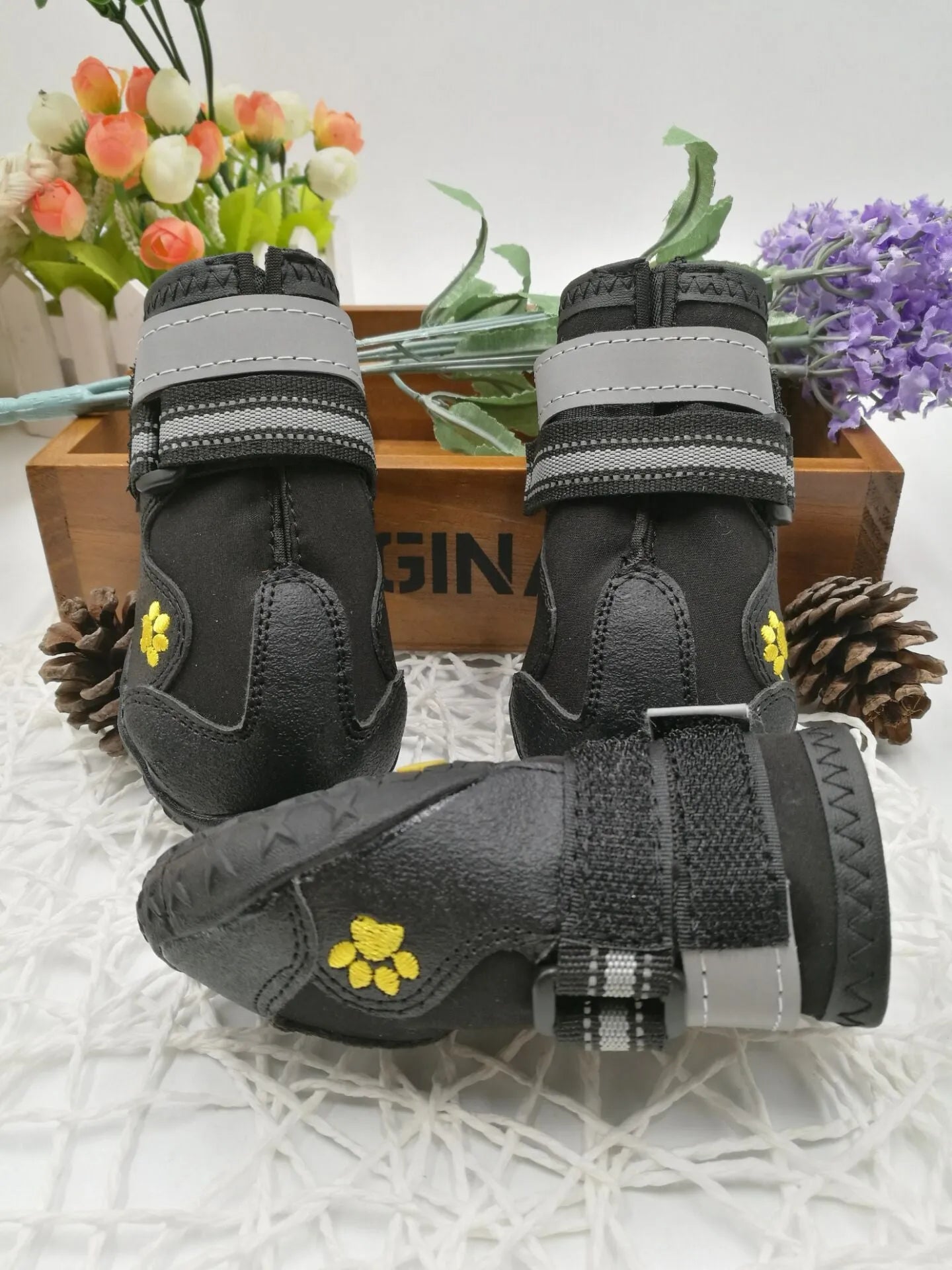 Black pet dog shoes with waterproof PVC sole and adjustable fuzzy belt on a light background