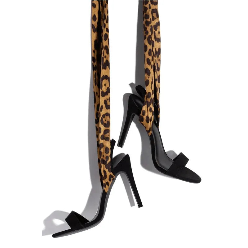 Light brown leopard print women's Roman sandals with cross-straps and a tall stiletto heel on a neutral background.
