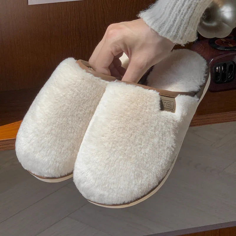 Pair of solid-colour plush winter slippers with a slip-on design and a textured PVC sole.