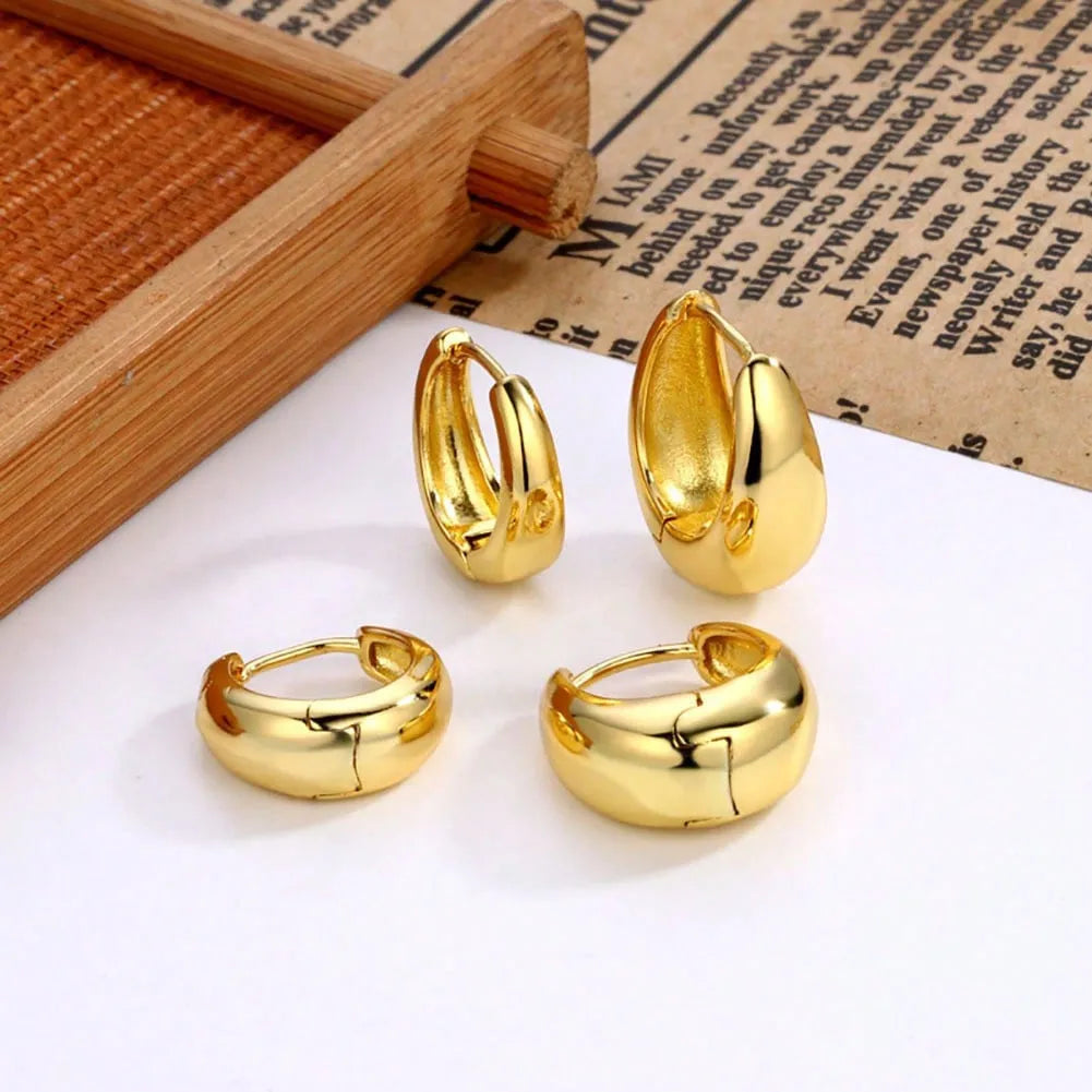 Three pairs of gold electroplated copper earrings with geometric ring design on a white background
