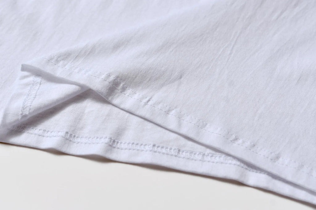 White cotton T-shirt overalls with a round neck and short sleeves, shown in a loose pullover style.