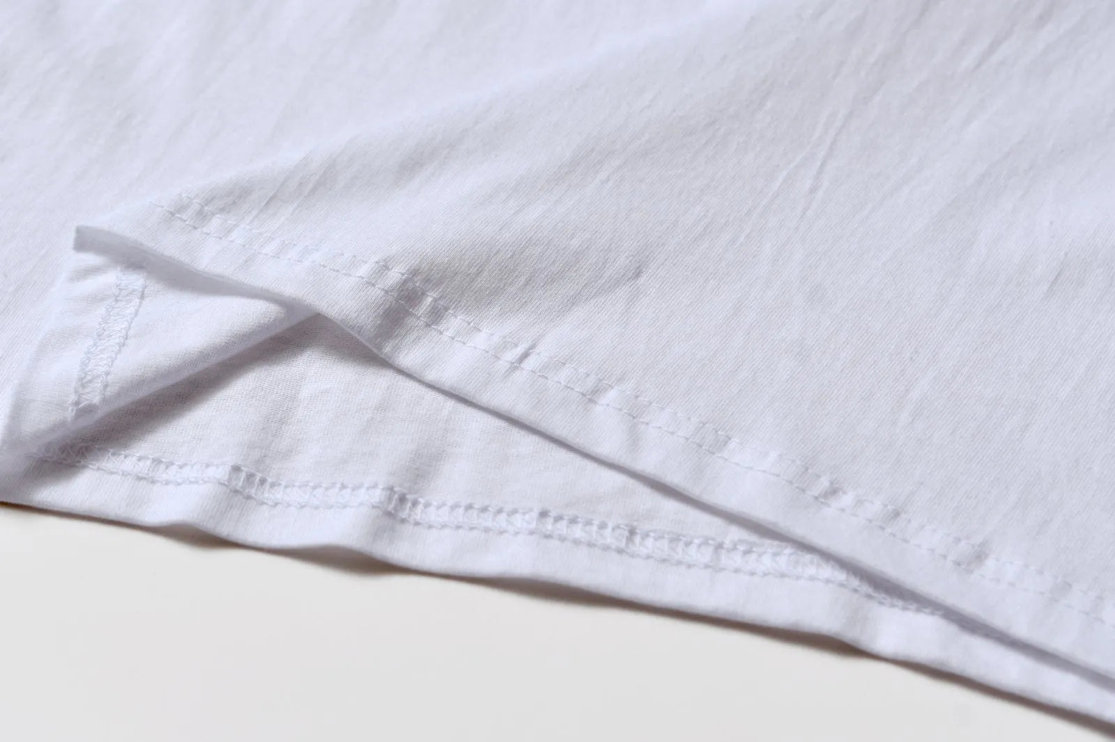 White cotton T-shirt overalls with a round neck and short sleeves, shown in a loose pullover style.