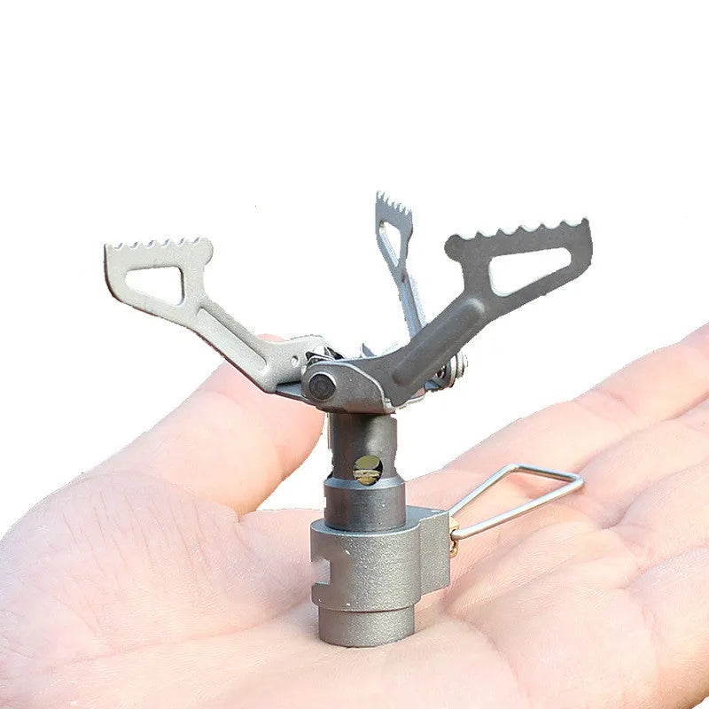 Compact portable propane camping stove with one-piece pressed steel furnace, black finish, and extended legs on a rocky surface.