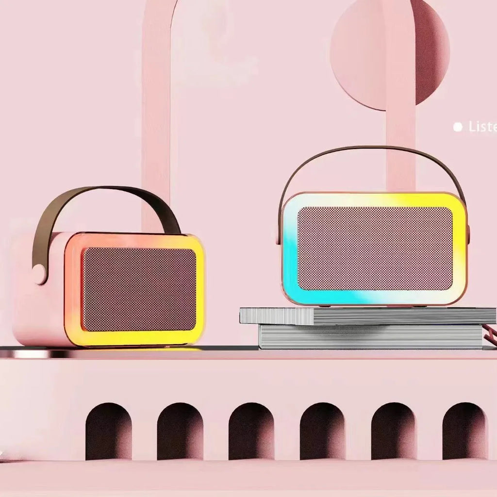 Pink Bluetooth speaker and microphone combo with coloured LED lights illuminated, placed on a table.