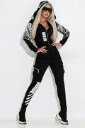 Black women's zip-up hoodie with wings print and matching casual trousers laid flat.