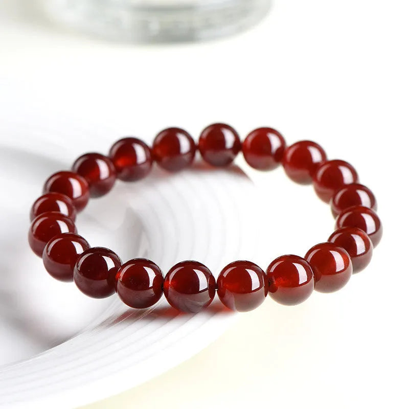 Natural orange red garnet ball bracelet with crystal beads and Ruyi design on a wrist.