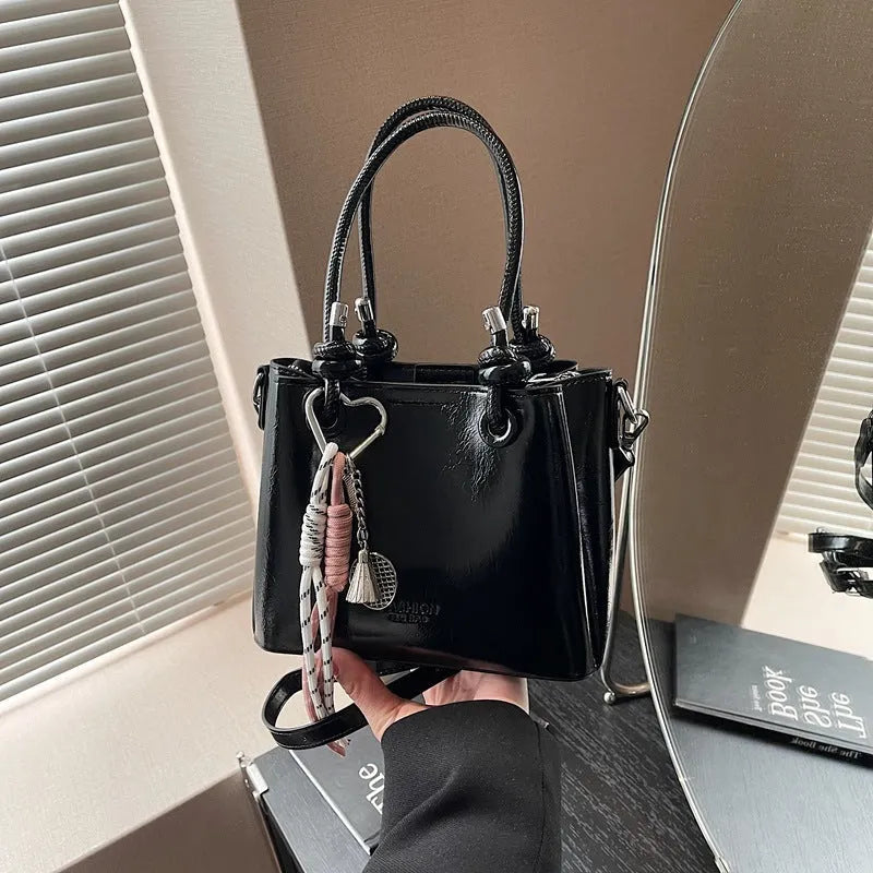 Women's PU one-shoulder bucket messenger bag in black with pendant, showing front view with single strap