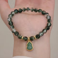 Handmade women's bracelet with a heart-shaped green phantom quartz pendant and pearl details on a crystal chain.