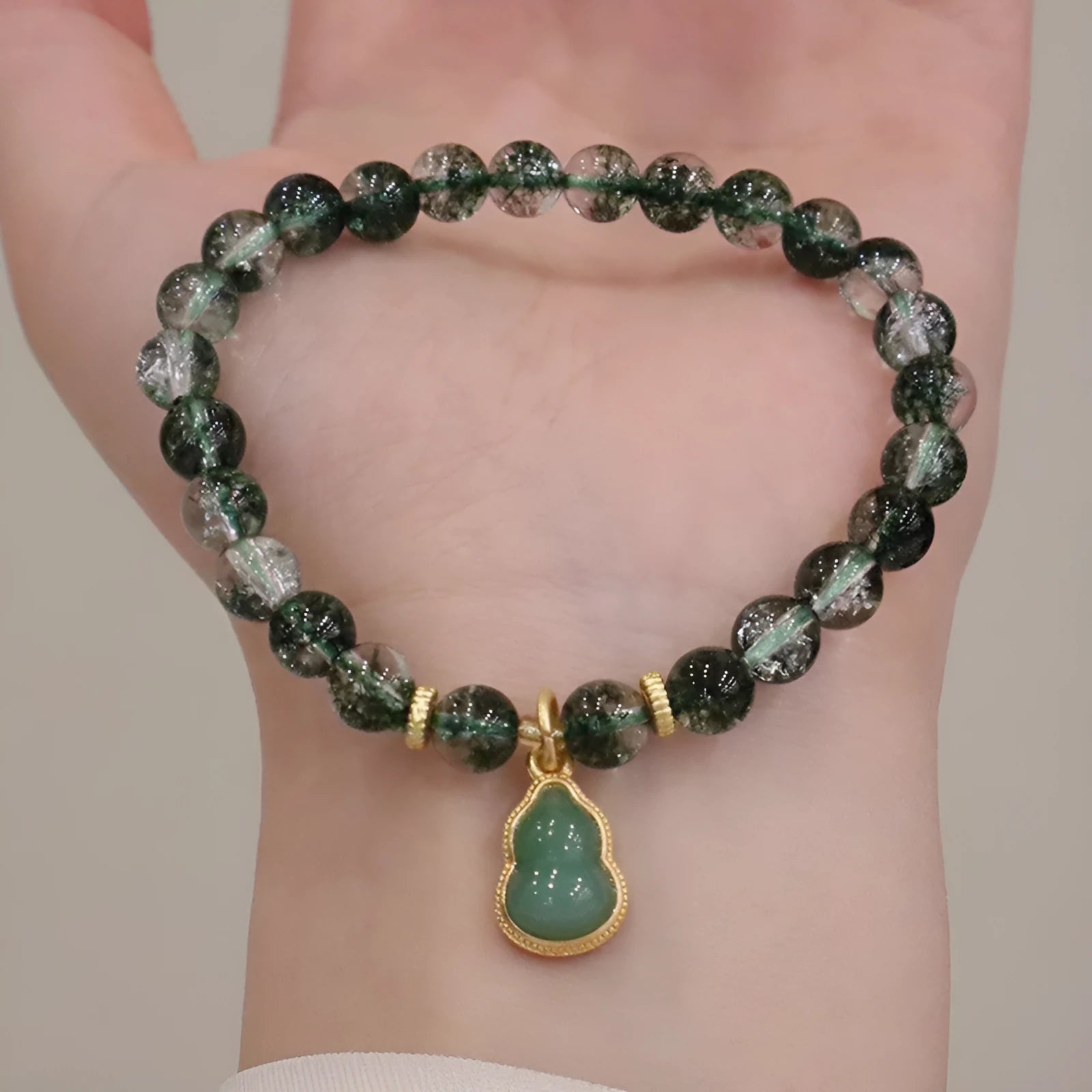 Handmade women's bracelet with a heart-shaped green phantom quartz pendant and pearl details on a crystal chain.