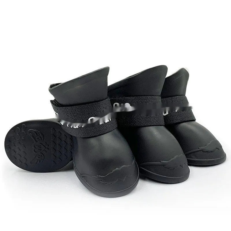 Set of four colourful rubber dog rain shoes with anti-slip soles on a wet surface.