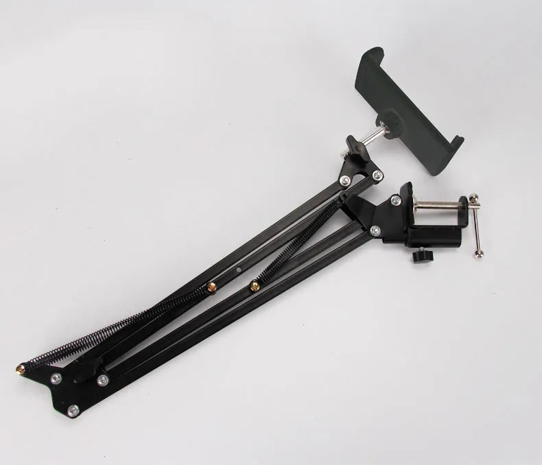 A black adjustable stand holding a mobile phone on a table.