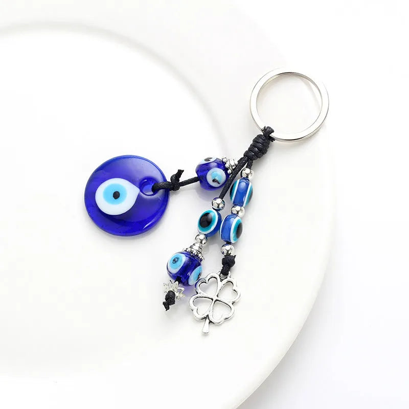 Blue metal eye of evil keychain 4cm pendant with plant-inspired design on grey background
