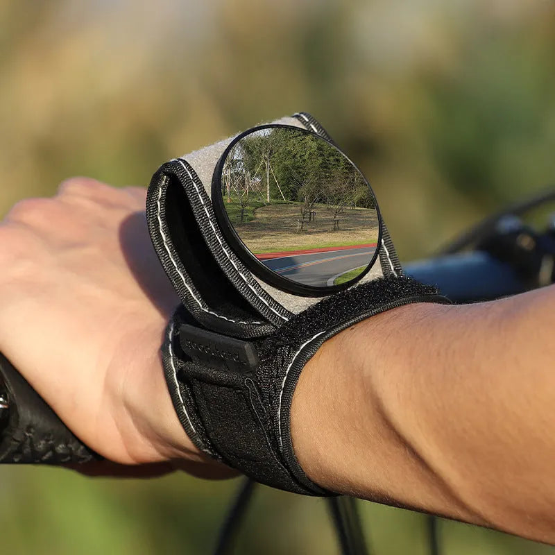 Black nylon bicycle rear-view mirror shown mounted on a cyclist's wrist.