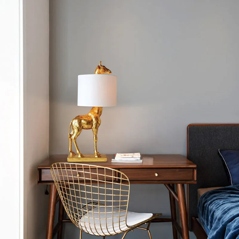 White giraffe table lamp with cloth shade on wooden bedside table