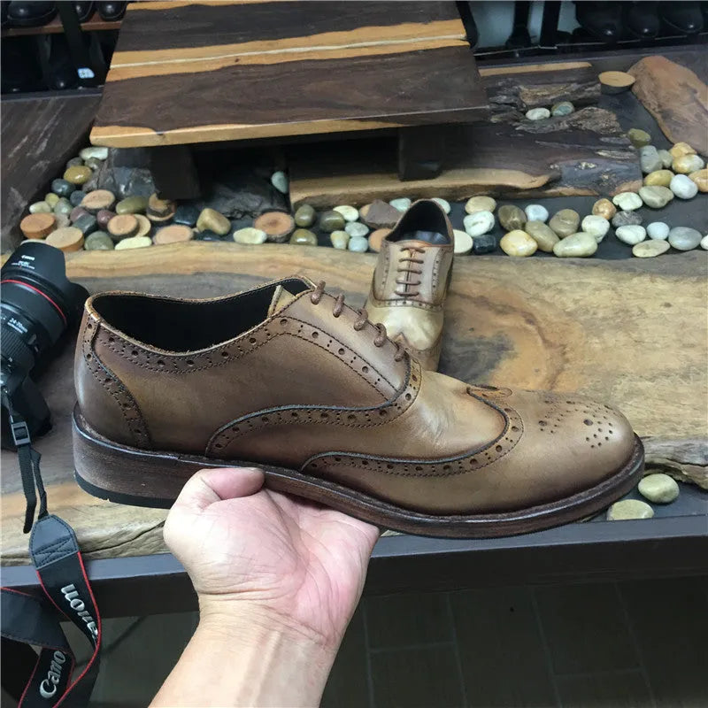 Light brown men's distressed leather lace-up shoes on a wooden surface, showing hand-carved details and round toe design.