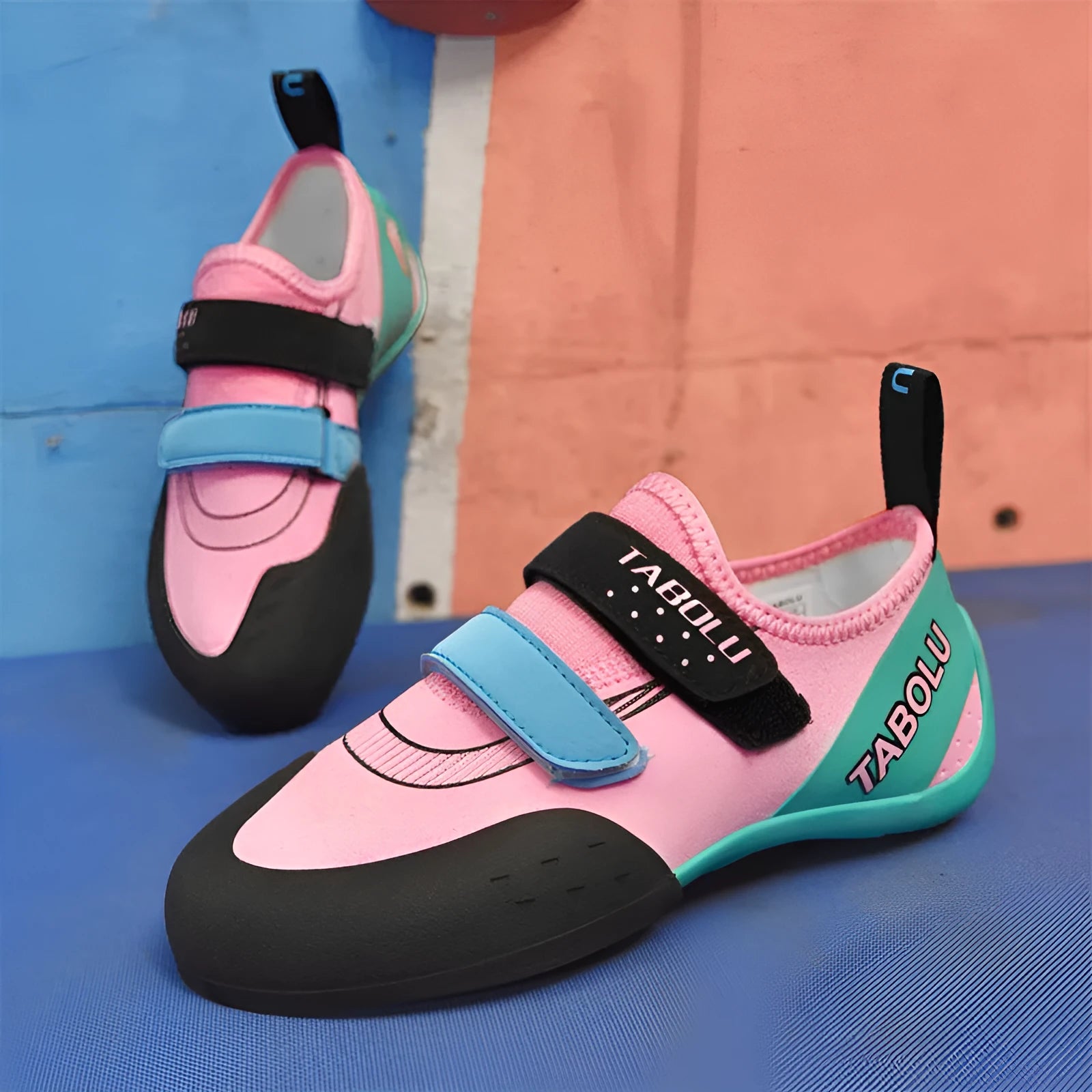 A pair of beginner rock climbing shoes with velcro straps in a black and red colour combination.