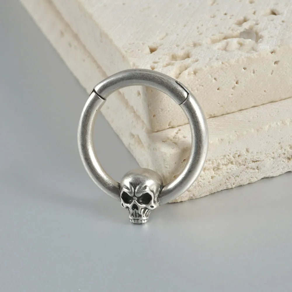 Close-up of vintage-style copper ghost head earrings with antique silver plating on a dark background.