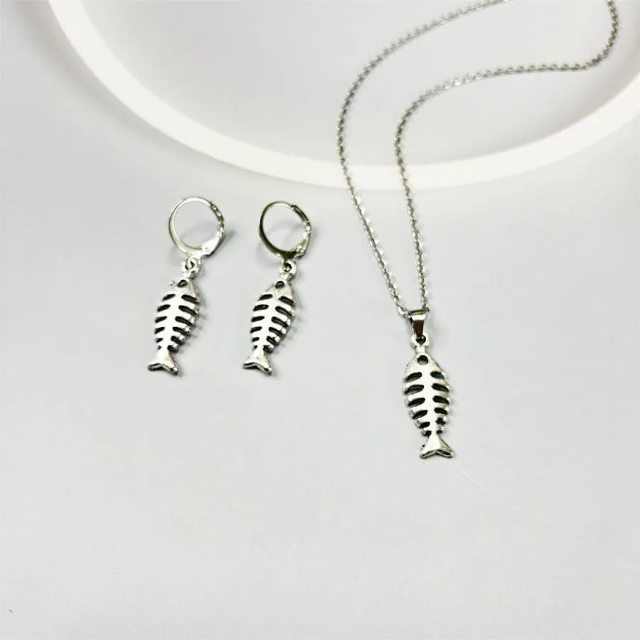 Fishbone pendant necklace and matching earrings set with adjustable chain on retro background