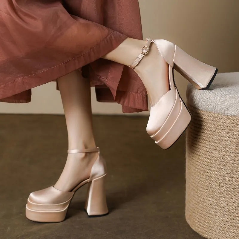 Women's white chunky heel platform pumps with a round toe and ankle strap on a plain background.
