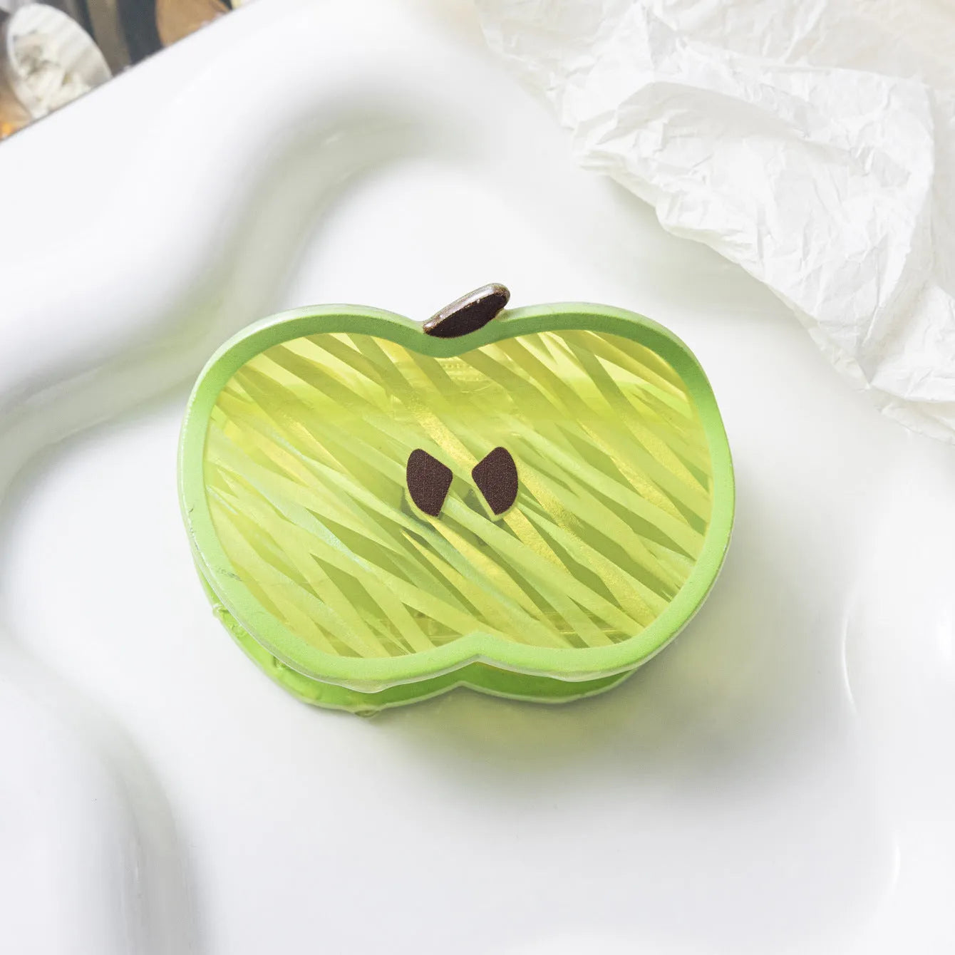 Green apple-shaped claw clip with polished PVC finish, 7.5cm long, on a plain background