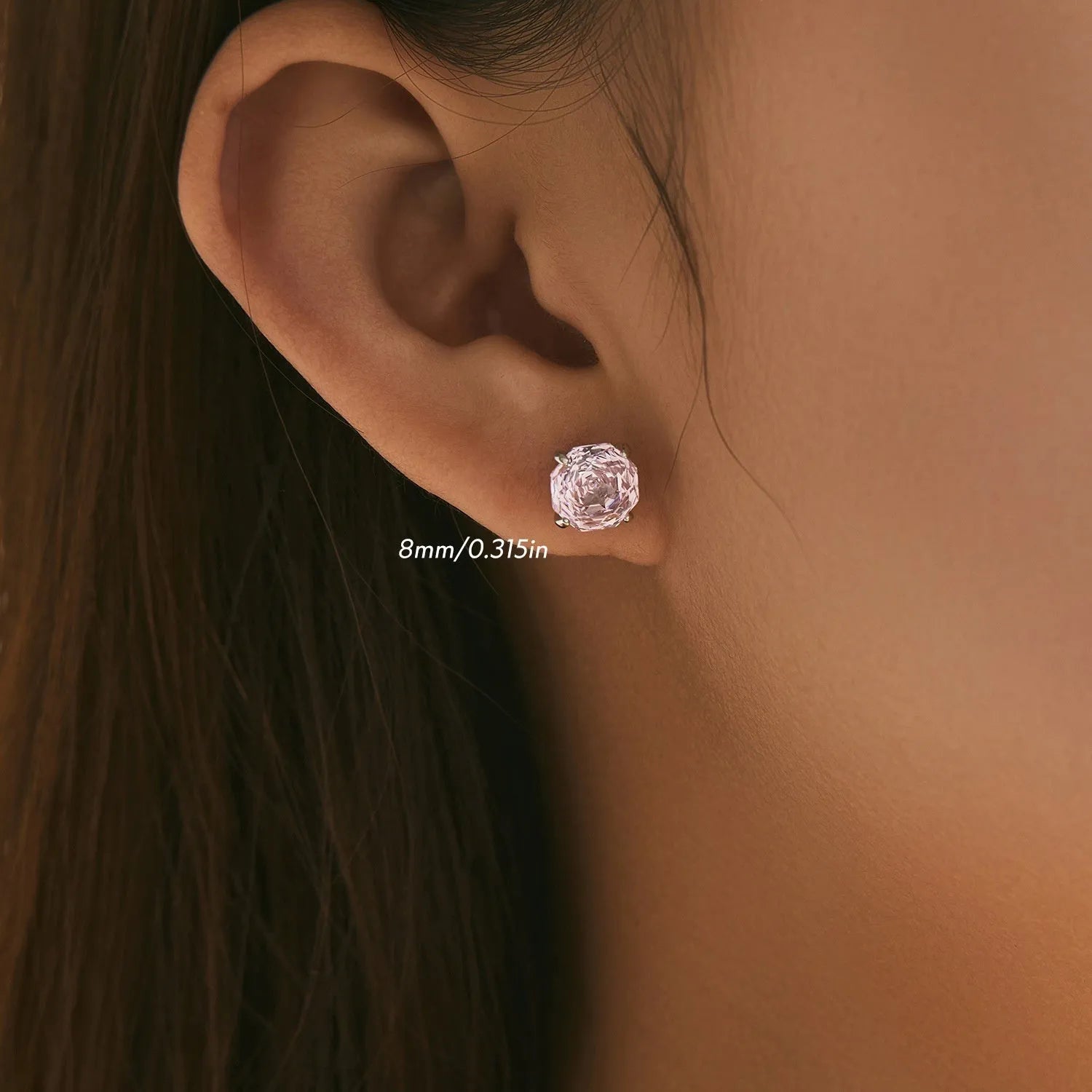 Close-up of a pair of pink S925 sterling silver rose-shaped stud earrings on a plain background.