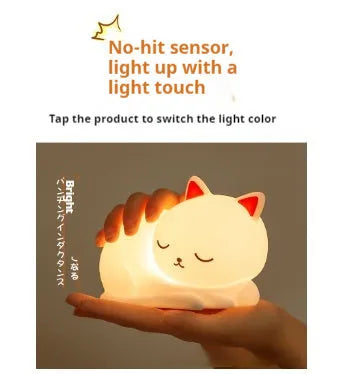 Sleepy cat shaped silicone induction night light with white glow on table