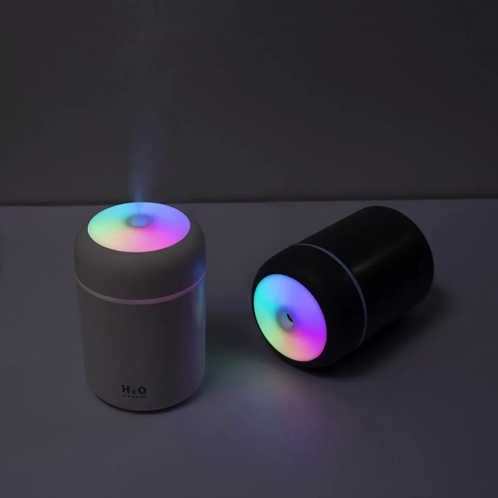 Pink USB desktop humidifier with colourful lights and water tank on wooden surface