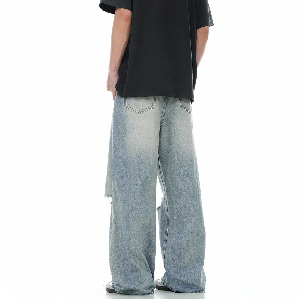 Blue men's straight-leg jeans with ripped details and a zip fly on a neutral background.