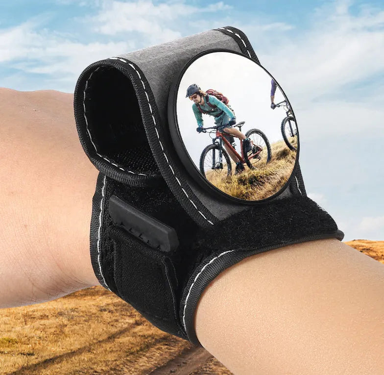 Black nylon bicycle rear-view mirror shown mounted on a cyclist's wrist.