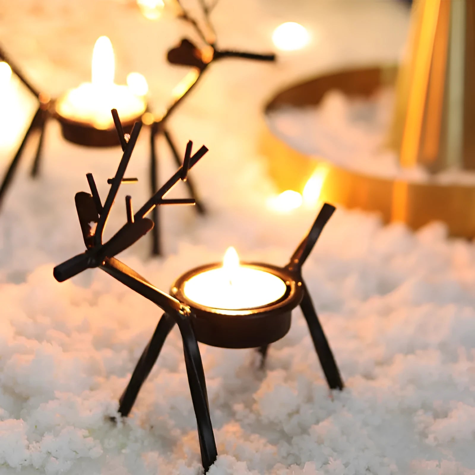 Black iron Christmas candlestick with deer and elk bracket design on a table.