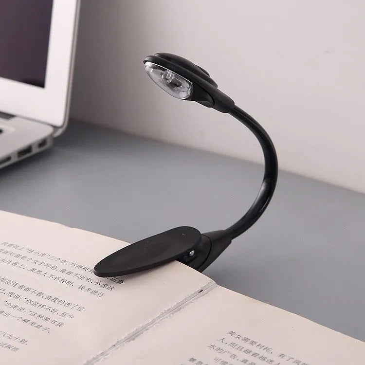 Mini clip-on LED book light with 26cm total length and metal clip on a book page