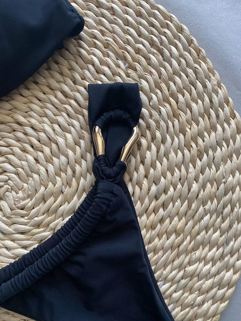 Black solid colour low-waist bikini swimsuit for women on a white background.