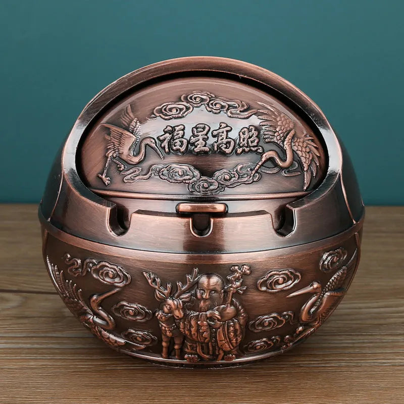 Bronze and red copper alloy decorative ashtray with smoke-extinguishing slot on a table.