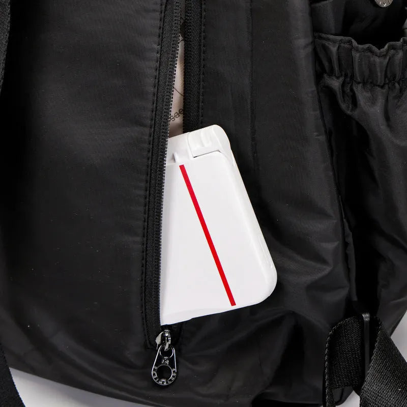 Large black nylon backpack with a front sandwich pocket, shown next to a khaki and a green graphic version.