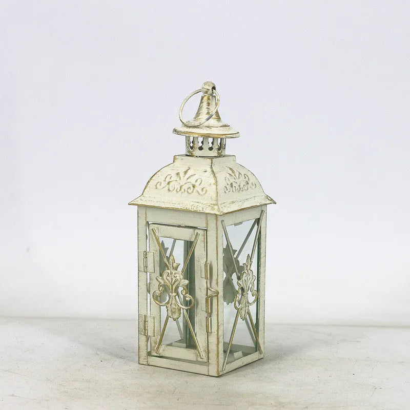 Black wrought iron floor-standing storm lantern with clear tempered glass panels on a garden patio.
