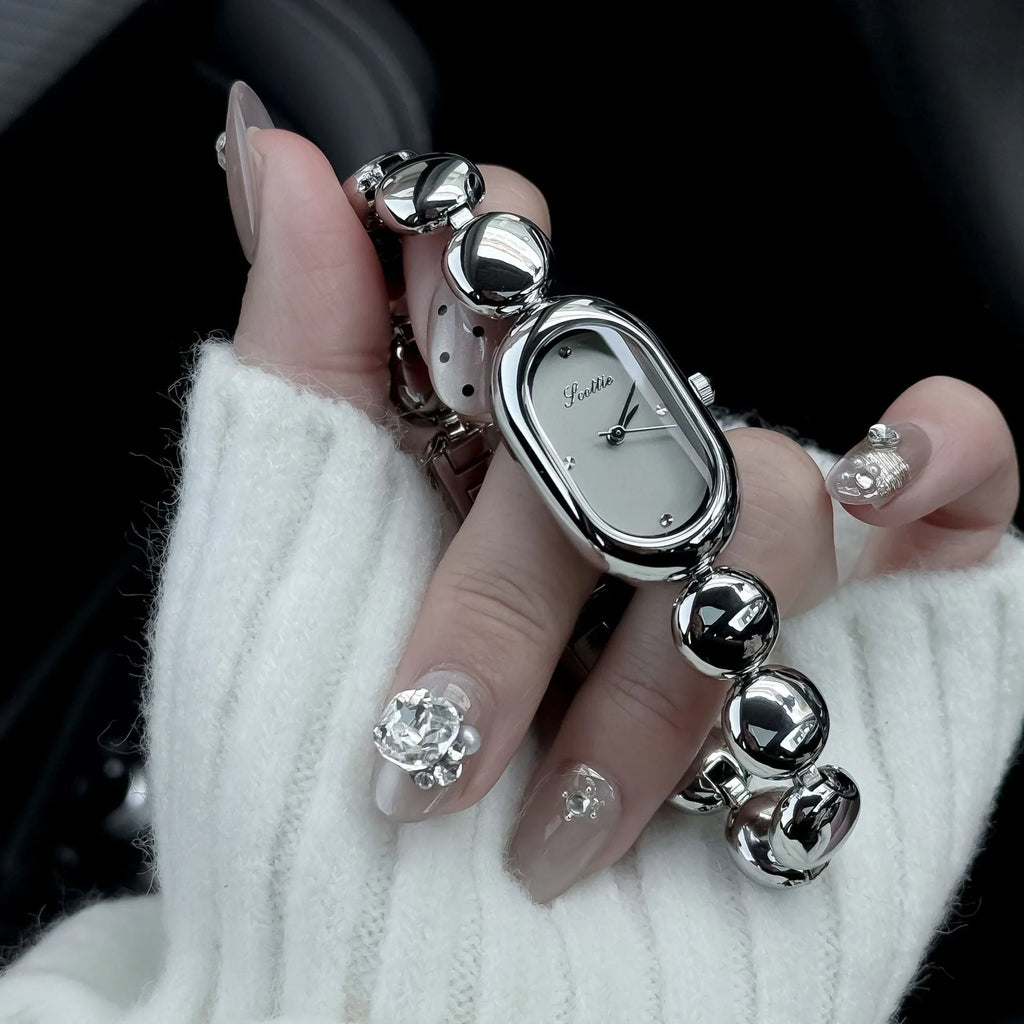 Oval women's fashion watch on wrist showing 9mm thick case, available in black gold, platinum and other colours.