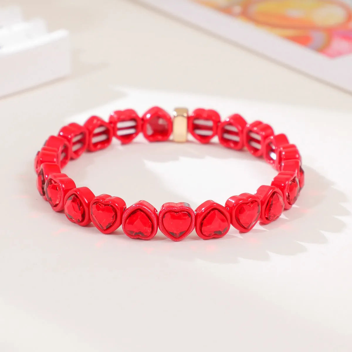 Colourful enamel heart-shaped pendant on a silver stretch bracelet.